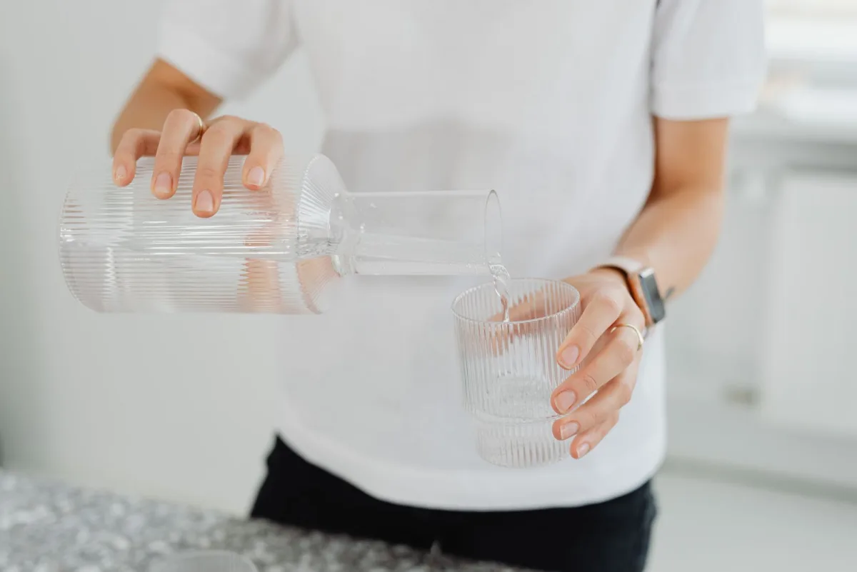 Clear, filtered water being poured into a glass in a bright modern kitchen